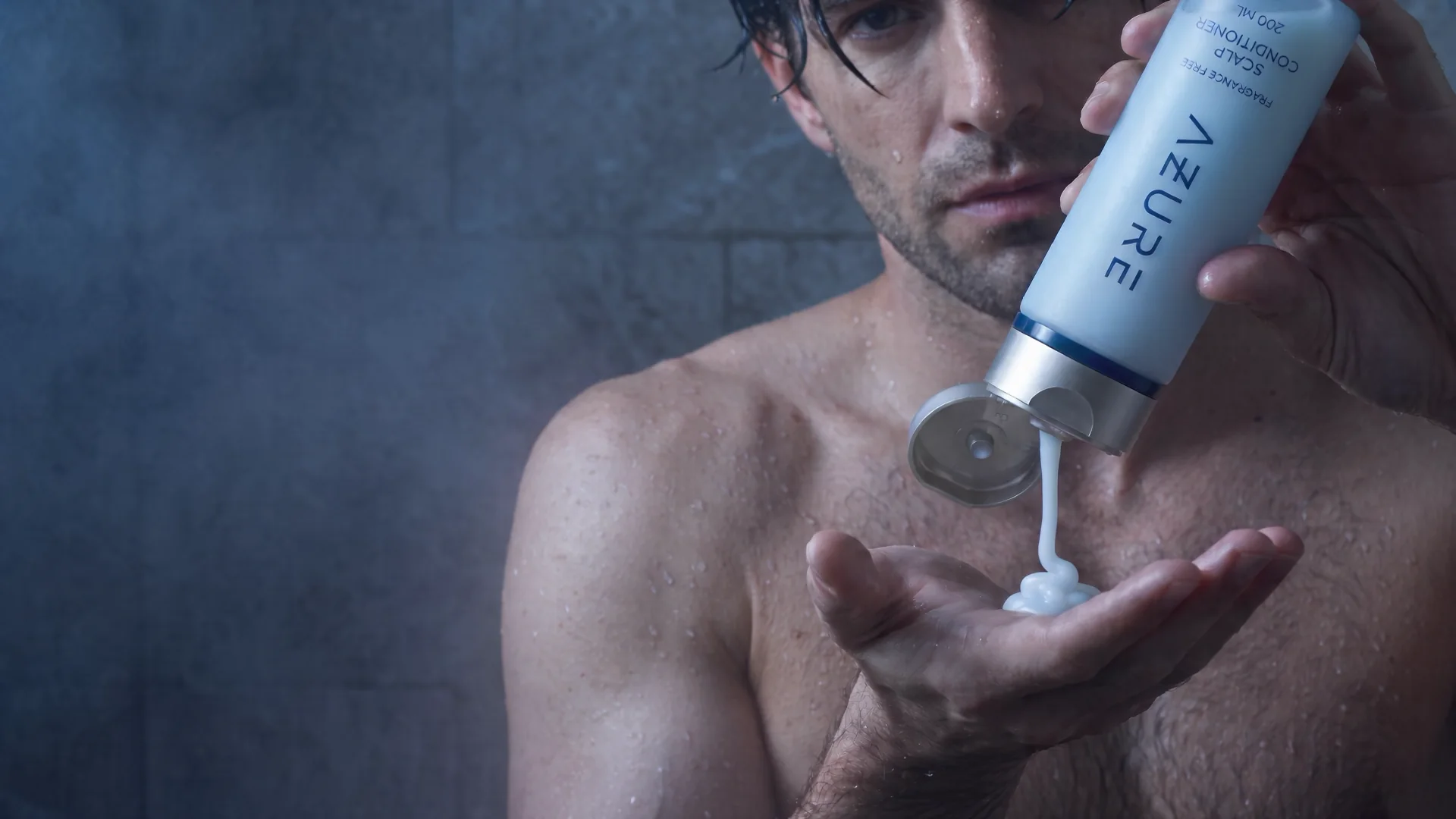 A man in the shower pouring AZURE Scalp Conditioner into his palm